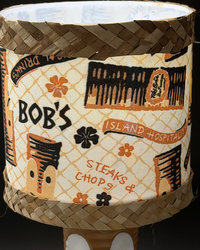 Tiki Bob tiki table lamp, lit, with vintage-inspired print shade