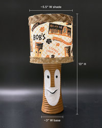 Tiki Bob tiki table lamp, lit, with vintage-inspired print shade