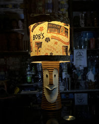 Tiki Bob tiki table lamp, lit, with vintage-inspired print shade