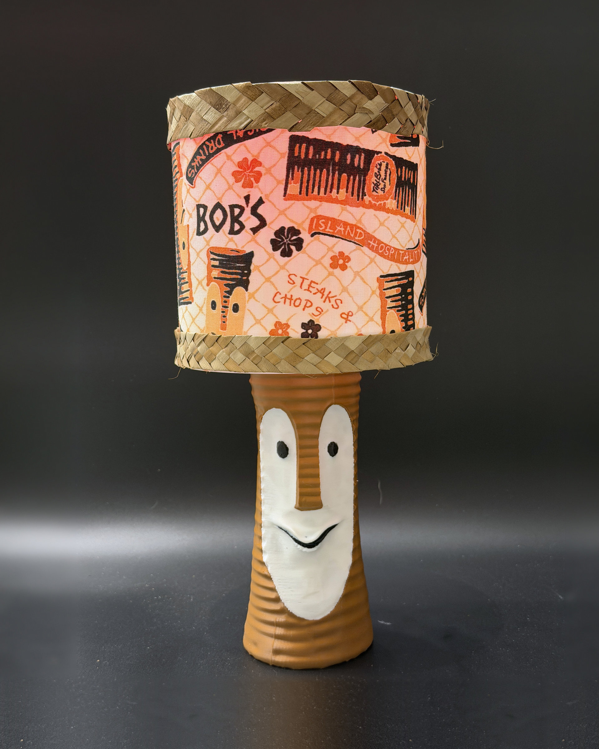 Tiki Bob tiki table lamp, lit, with vintage-inspired print shade