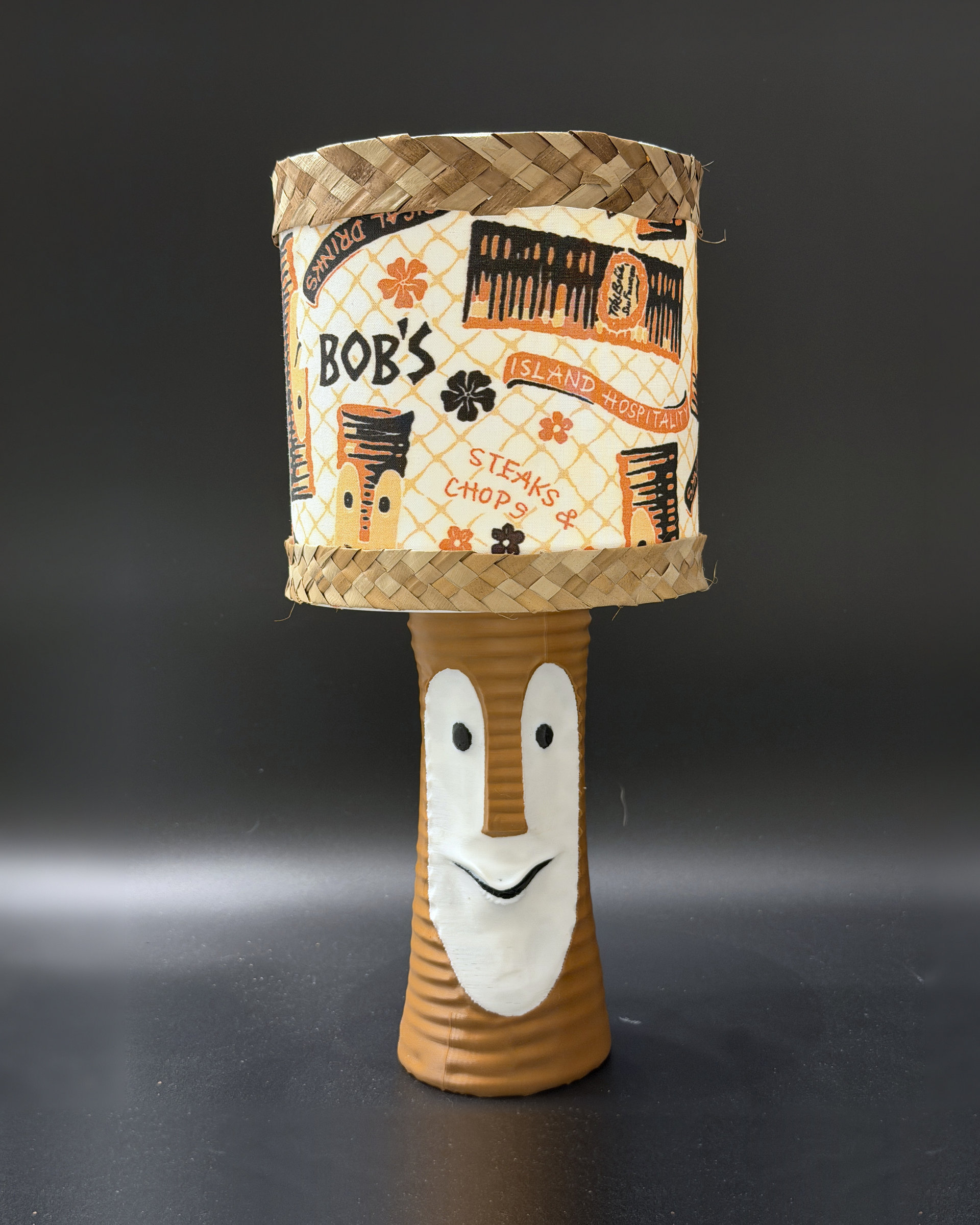 Tiki Bob tiki table lamp, lit, with vintage-inspired print shade