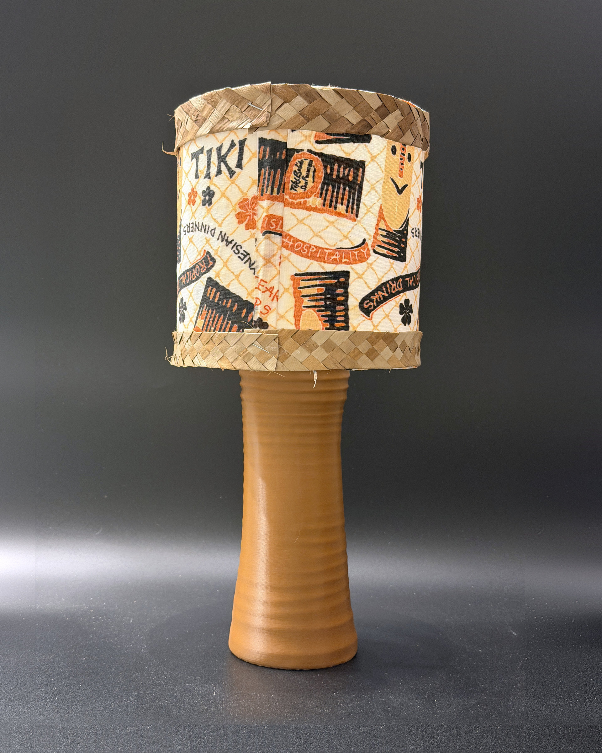 Tiki Bob tiki table lamp, lit, with vintage-inspired print shade