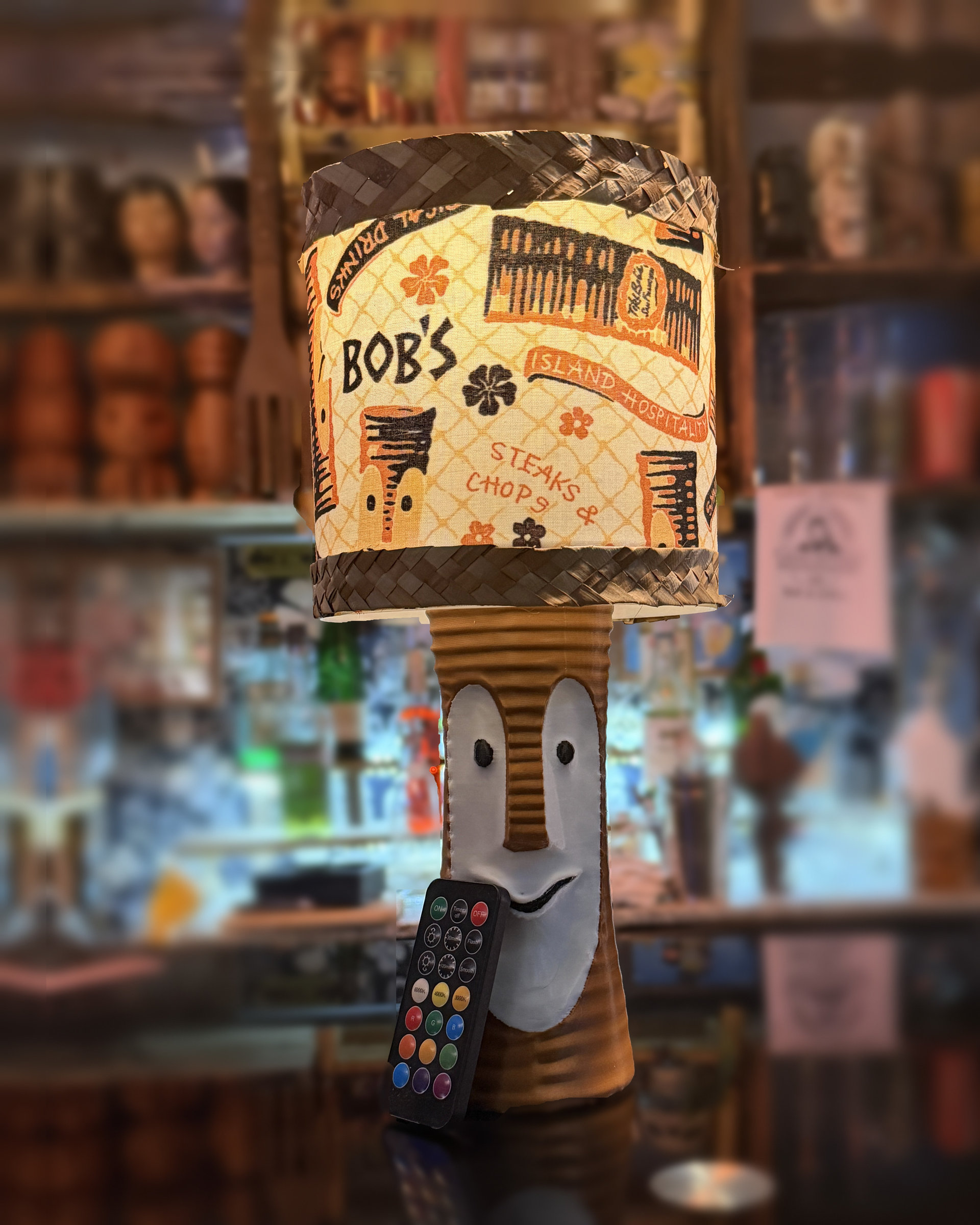 Tiki Bob tiki table lamp, lit, with vintage-inspired print shade