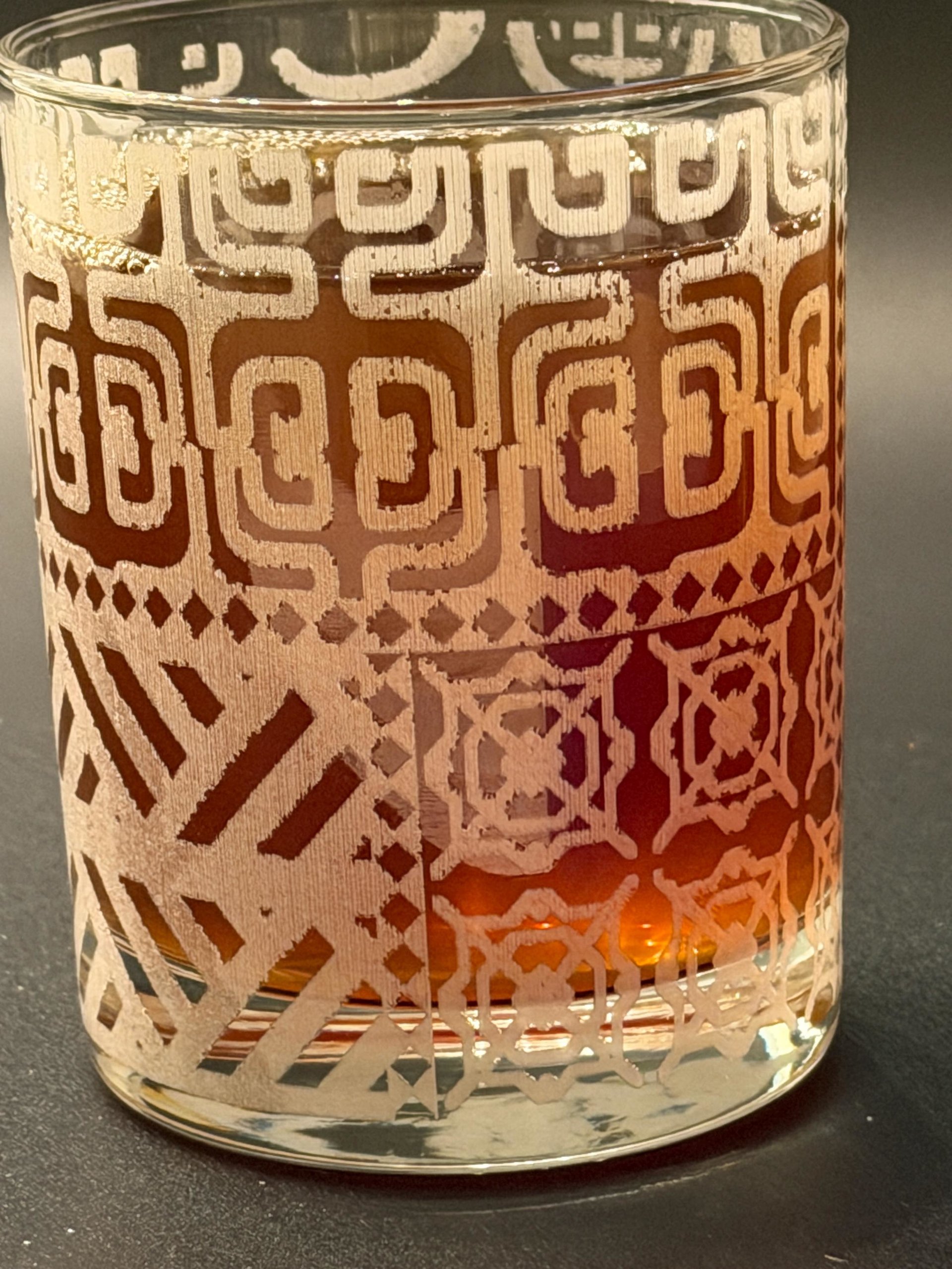 Filled rocks glass close-up showing the Tapa spiral and diamond pattern.