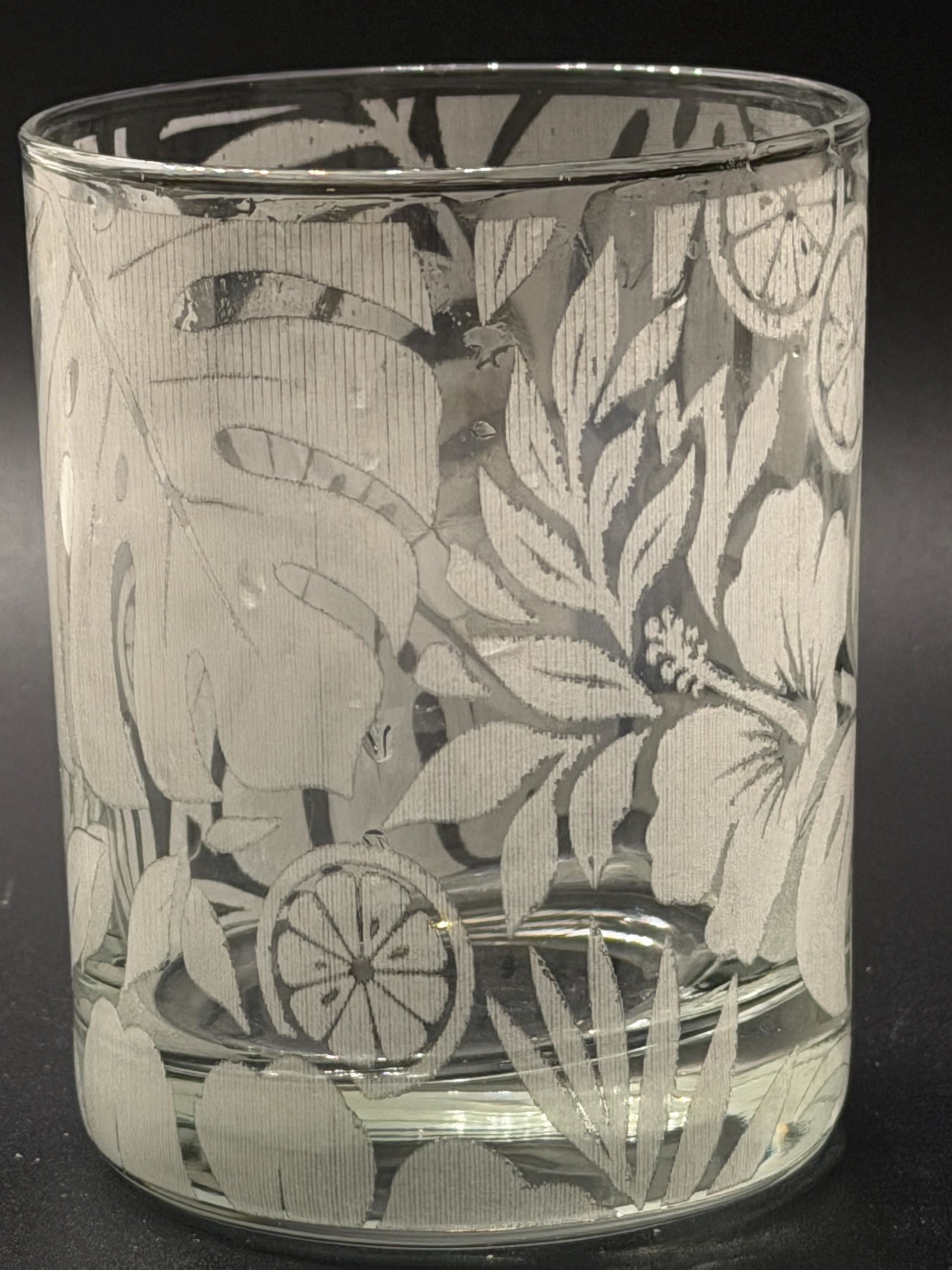 Empty rocks glass close-up showing Tropical flowers, foliage and citrus etching.